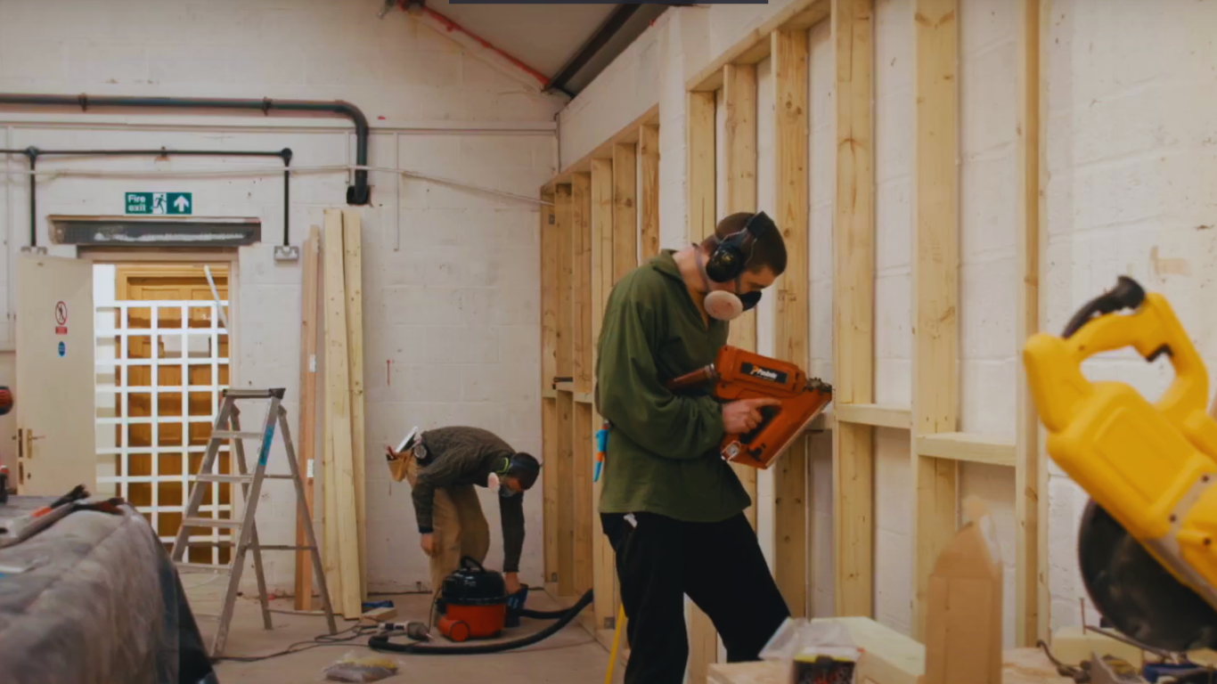 Two men working on improving an office space with match funding.