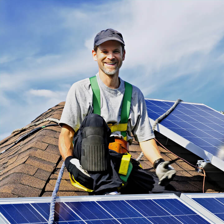 man smiling at camera while installing solar panels