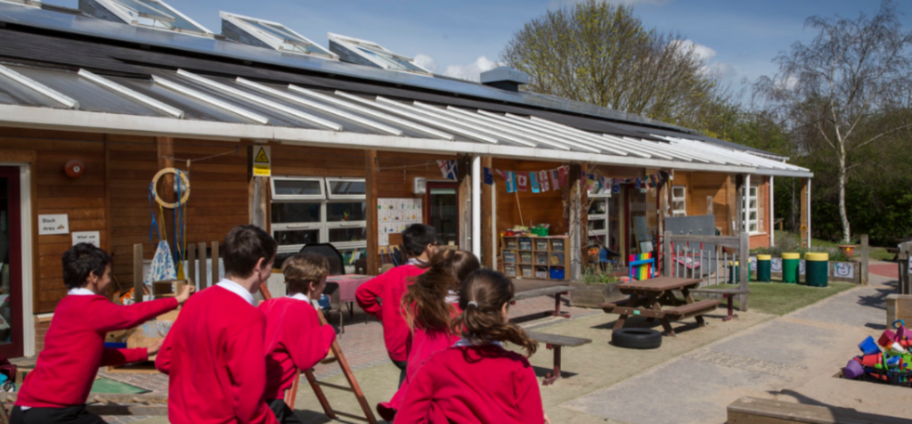 School children running in front of solar panels on a school roof.
