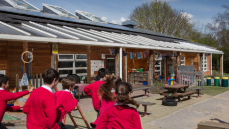 School children running in front of solar panels on a school roof.