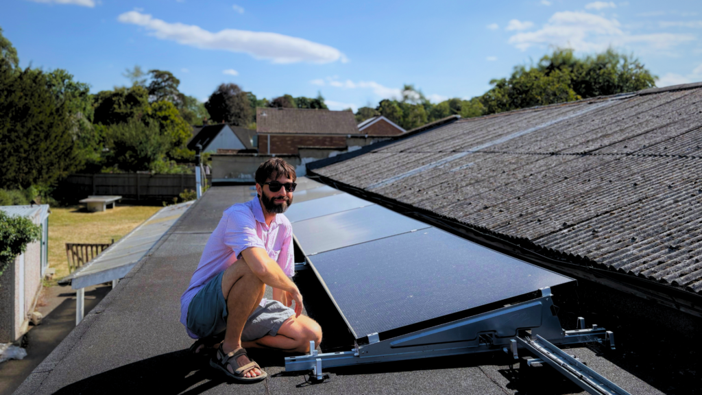 Florence Park Community Centre roof covered in solar panels. Danny Chivers, Treasurer, sits next to them.