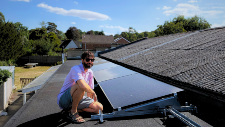 Florence Park Community Centre roof covered in solar panels. Danny Chivers, Treasurer, sits next to them.